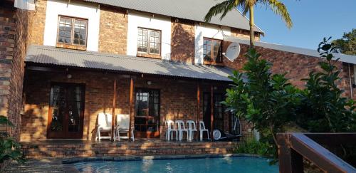 a house with chairs and a swimming pool at Protea Lodge in Port Elizabeth