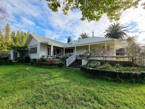 a white house with a yard at Country Garden Oasis with Parking and Wi-Fi in Taupaki