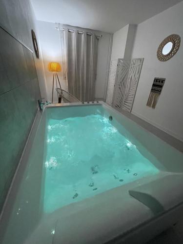 - une baignoire avec de l'eau bleue dans la chambre dans l'établissement Le Châteaucreux - Cosy & SPA, à Saint-Étienne