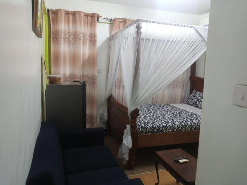 a bedroom with a canopy bed and a chair at SAFI Apartment in Mombasa