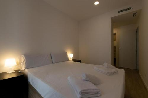 una camera da letto con un letto bianco e asciugamani di Apartamentos Mercado Central a Valencia