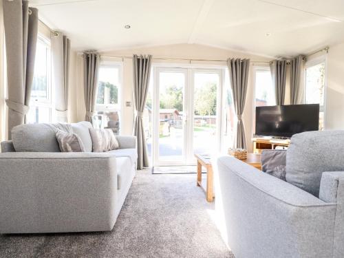 a living room with two couches and a tv at Hawthorn Lodge in Carnforth