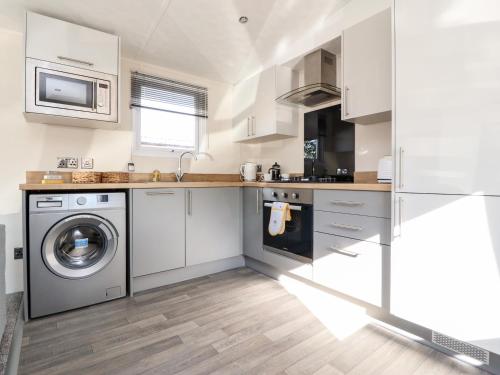 a kitchen with white cabinets and a washer and dryer at Hawthorn Lodge in Carnforth