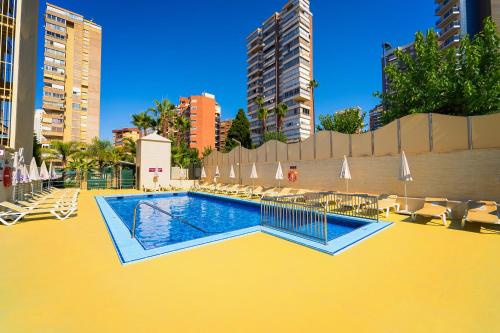 a pool with chairs and umbrellas on a yellow floor at Hotel Servigroup Diplomatic in Benidorm