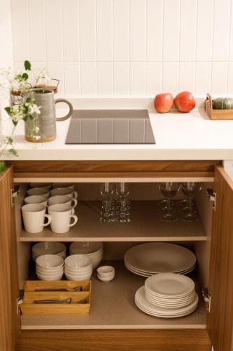 a kitchen with a sink and plates in a cabinet at White Linen House in Seoul
