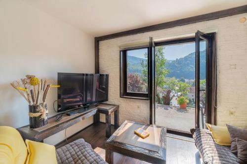 a living room with a tv and a large window at Apartments Vidik in Ivanjica