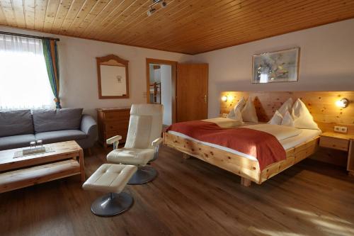 een slaapkamer met een groot bed en een bank bij Sportbauernhof - Gasthaus Hochalmblick in Eisentratten