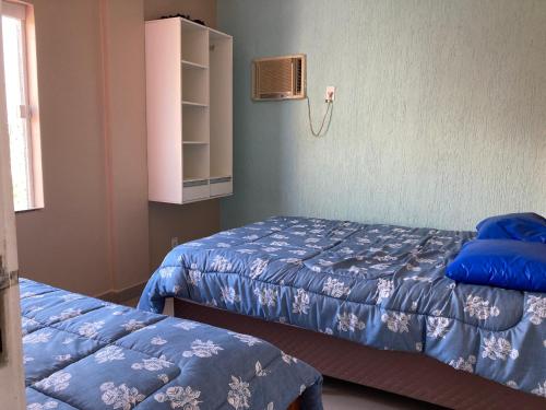 Habitación con 2 camas con sábanas azules y ventana en Vista mar, duplex a 20 mts praia do forte, jacuzzi e wifi, en Cabo Frío