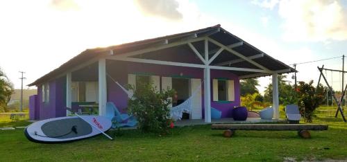 une petite maison violette avec une planche de surf devant elle dans l'établissement Pousada Igrejinha dos Carneiros, à Tamandaré