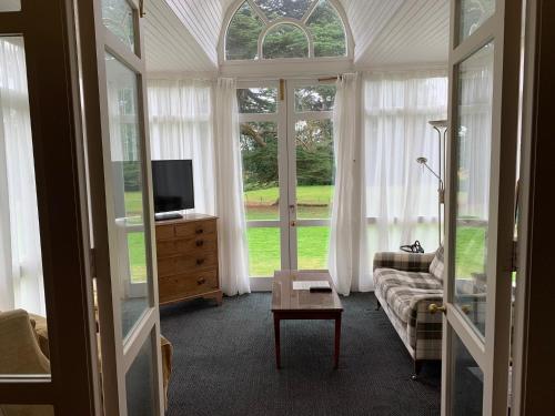 a living room with a couch and a tv and windows at Flitwick Manor Hotel in Flitwick