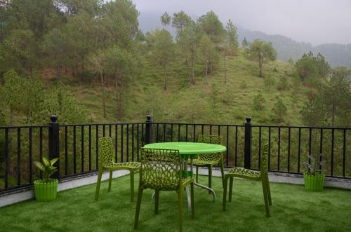a green table and chairs on a balcony with a view at Hotel The Paal in Shimla