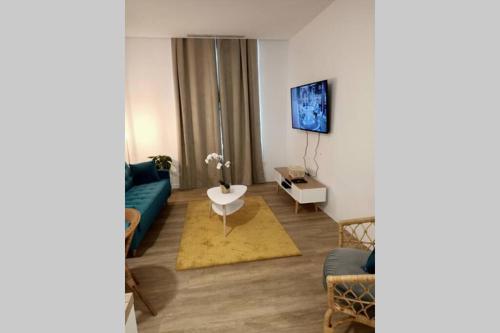 ein Wohnzimmer mit einem Sofa und einem TV an der Wand in der Unterkunft Appartement Montpellier Comédie Gare St Roch in Montpellier