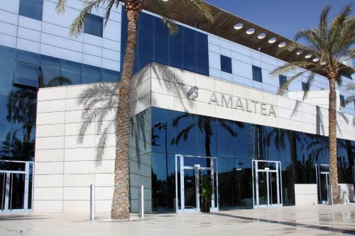a building with palm trees in front of it at Hotel Amaltea by Executive Sport in Lorca