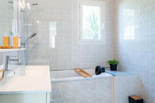 uma casa de banho branca com uma banheira e uma janela em Le Petit Thao em Fréjus
