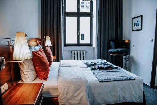 a bedroom with a bed and a lamp and a window at B&B Hotel Praha in Nový Jičín