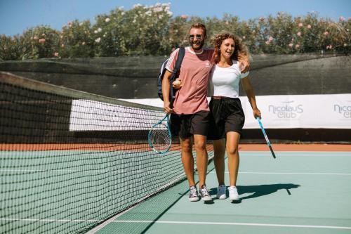 a man and a woman standing on a tennis court at Nicolaus Club La Giurlita in Ugento