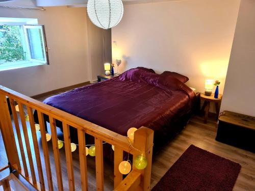 1 dormitorio con 1 cama con edredón morado en La Ferme des lutins, en Amancy