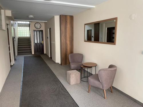 pasillo con 2 sillas, mesa y espejo en Hana Apartments Prishtina, en Pristina