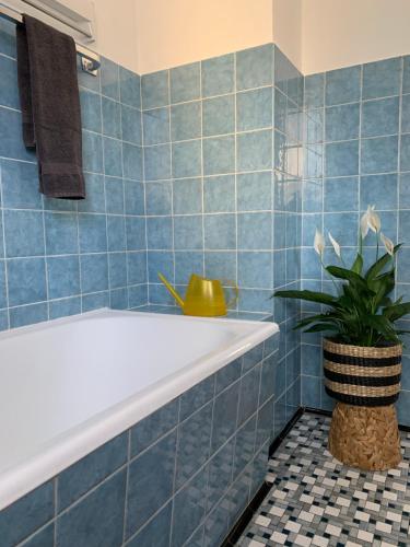 baño de azulejos azules con bañera y planta en Ferienwohnung Das Inge De Unterne en Bernau am Chiemsee