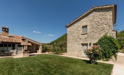 an exterior view of a stone house with a yard at I Casali di Villa Benveduti in Gubbio
