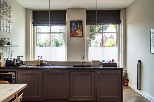 a kitchen with a sink and two windows at B&B Amsterdam Amstel Apartment in Amsterdam