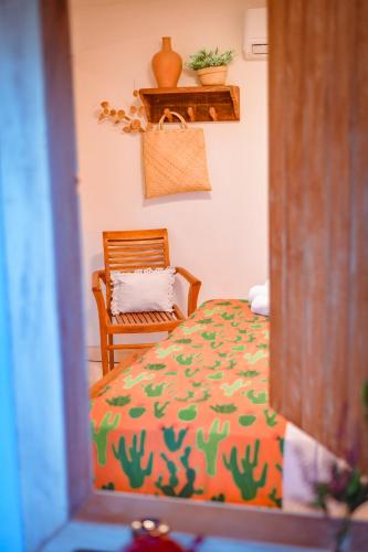a bedroom with a bed and a wooden chair at EcoCharme Pousada Netuno in Fernando de Noronha