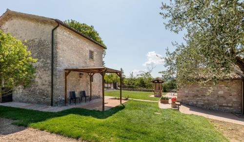 a garden with a stone building with a gazebo at I Casali di Villa Benveduti in Gubbio