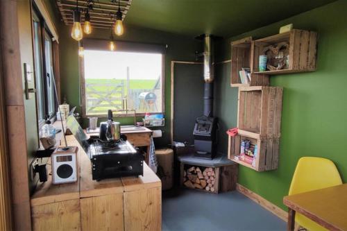 a room with a kitchen with a stove and green walls at The Bolt Hole in St Merryn