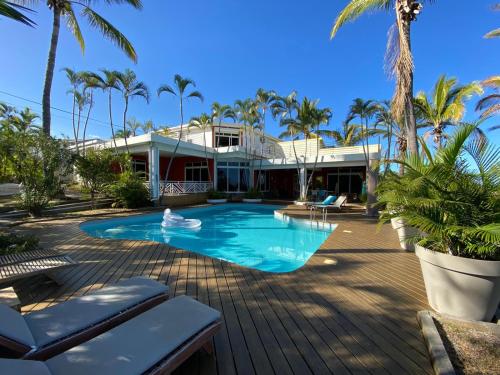a swimming pool in front of a house with palm trees at Villa Prana in La Saline les Bains