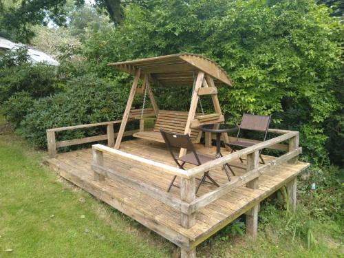 a wooden deck with a gazebo and two chairs at The Woodstore in Dunkeswell