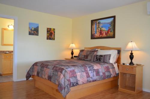a bedroom with a bed with two night stands and two lamps at Dogwood Bed & Breakfast in Summerland