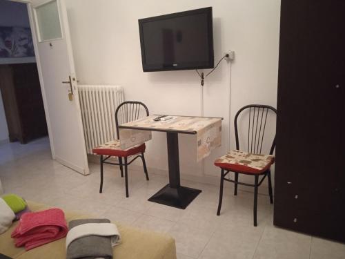 um quarto com uma mesa e duas cadeiras e uma televisão em I Tre Leoni Affittacamere em Civitavecchia