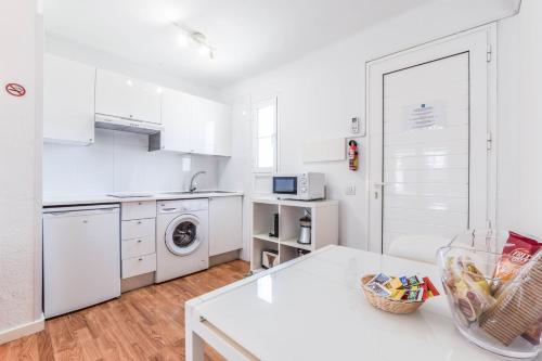 a kitchen with white cabinets and a white table at Villas New Lanzasuites in Playa Blanca