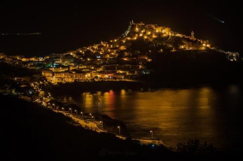 a city lit up at night next to the water at La terra del benessere in Castelsardo