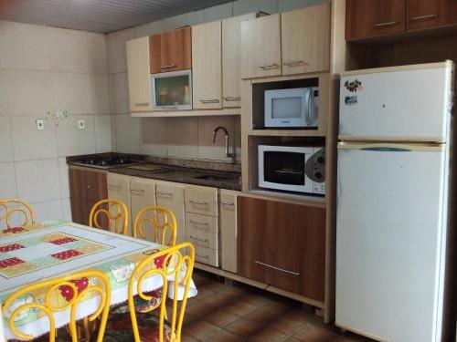 a kitchen with a table and a white refrigerator at Casa a uma quadra da praia da Armação in Florianópolis