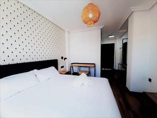 una camera con letto bianco e lampadario pendente di Hotel Matilde by gaiarooms a Salamanca