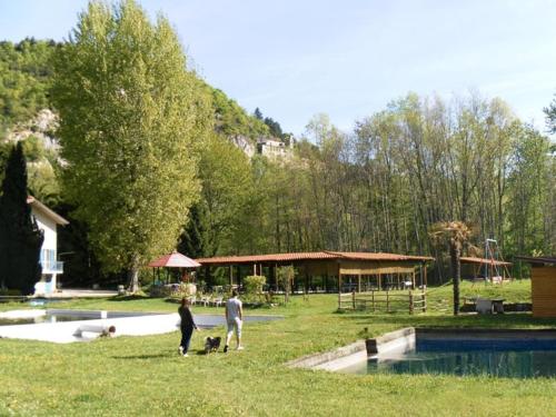 twee mensen en twee honden in het gras bij een zwembad bij Agriturismo S.Lucia in Roccaforte Mondovì