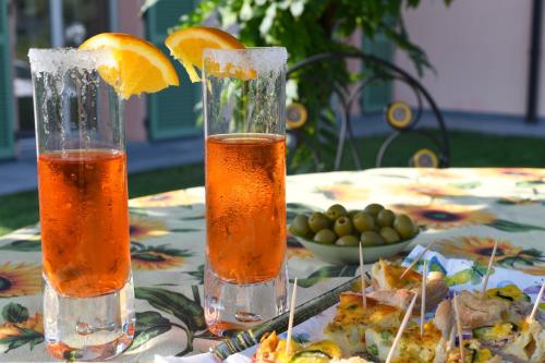 two glasses of drinks on a table with a plate of food at La Casa Della Volpe in Vedano Olona
