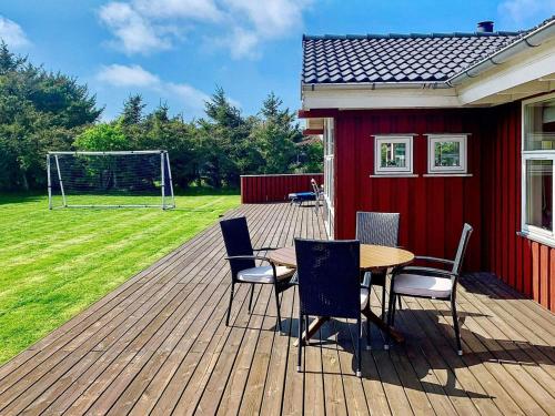 eine Holzterrasse mit einem Tisch und Stühlen und einem Tor in der Unterkunft 6 person holiday home in L kken in Løkken