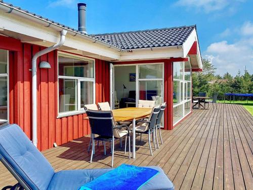 eine Holzterrasse mit einem Tisch und Stühlen auf einem Haus in der Unterkunft 6 person holiday home in L kken in Løkken