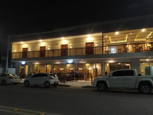 two cars parked in front of a building at night at Pousada BarbacoaR in Parnaíba