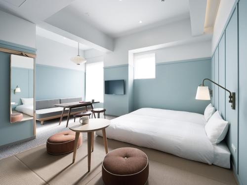 a bedroom with a bed and a table and chairs at RAKURO Kyoto by THE SHARE HOTELS in Kyoto