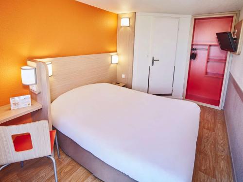 a bedroom with a white bed and a red door at Première Classe Nantes Sud - Rezé Aéroport in Rezé