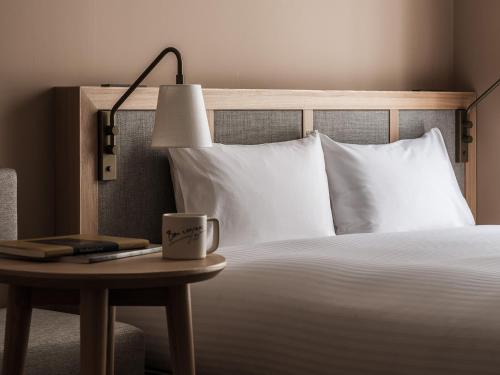 a bed with a lamp and a cup on a table at RAKURO Kyoto by THE SHARE HOTELS in Kyoto