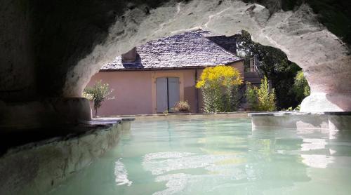 una piscina d'acqua con una casa sullo sfondo di Domaine Le Mayne a Chabrignac