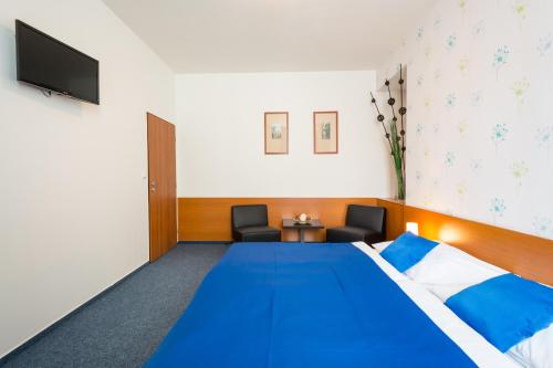 a hotel room with a blue bed and a tv at Adeba Hotel in Prague