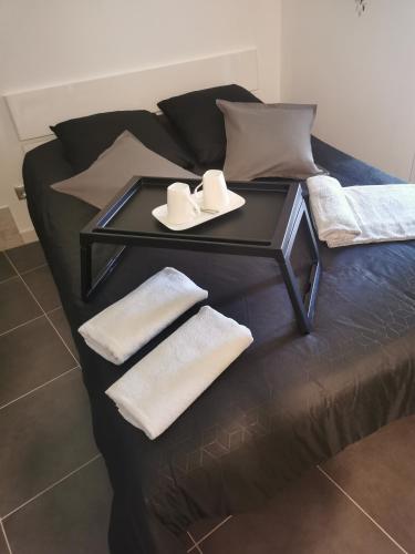 a black bed with a tray with hats and towels on it at Jacuhomespa13 in Vitrolles