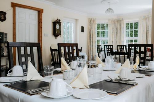 a dining room with a table with white plates and napkins at Glenhill B&B in Wexford