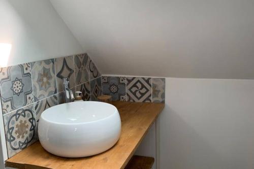 a bathroom with a white sink on a wooden counter at LA PETITE MAISON PRÈS DE LA MER in Fécamp