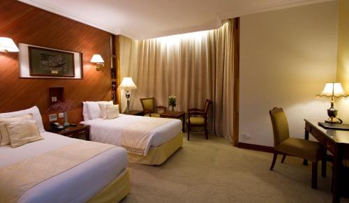 a hotel room with two beds and a desk at Palace Hotel Arusha in Arusha